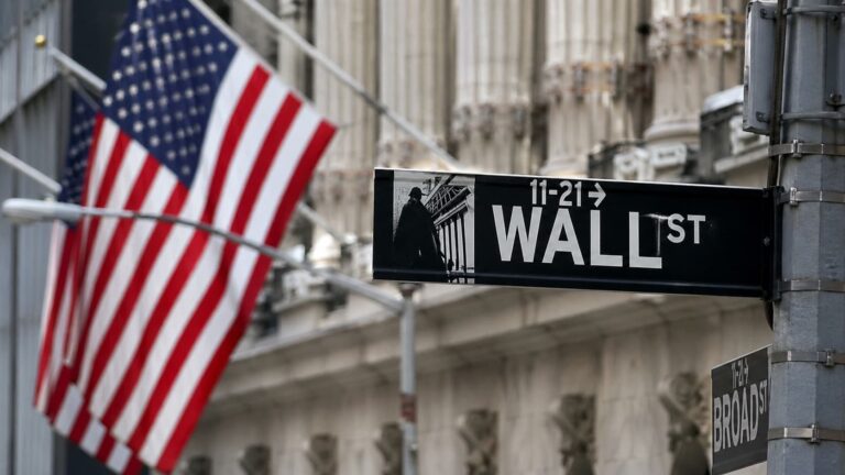 Wall Street sign with flag backdrop